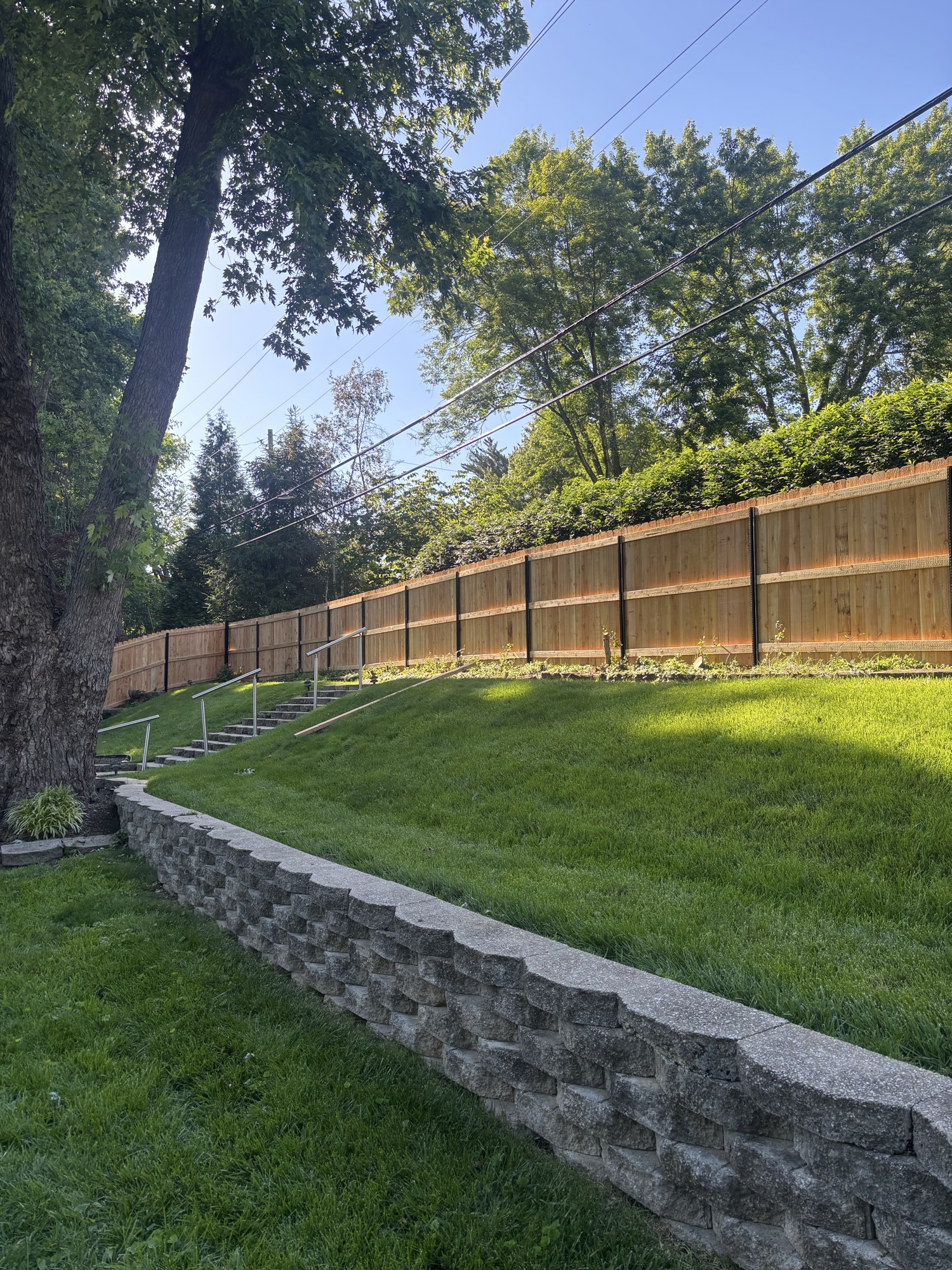 Stone retaining wall with cedar fence on hillside property